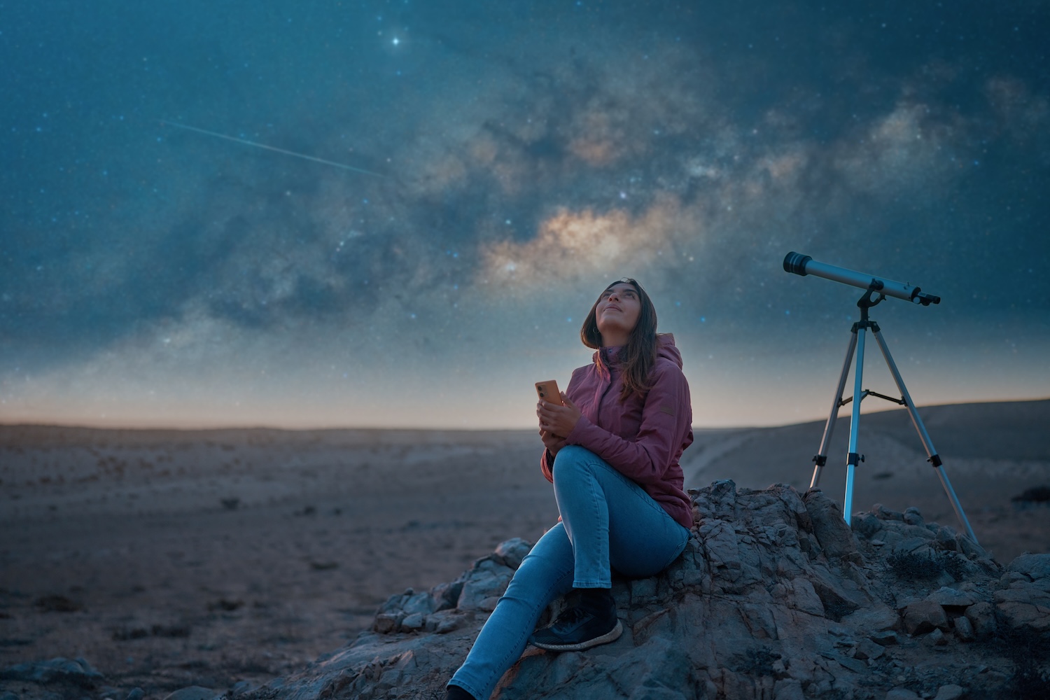 Latina woman sitting in the desert alone watching the starry sky and the milky way in the background